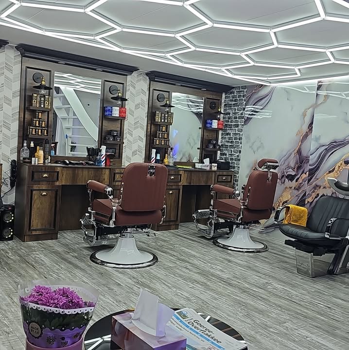 De zaak van Barbershop Flakkee met twee leren barbierstoelen, houten spiegelmeubels en een plafond met lichtstrips