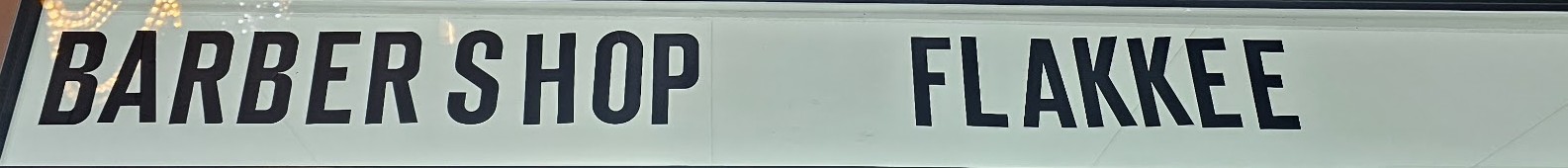 Het uithangbord boven de deur: Barber Shop Flakkee